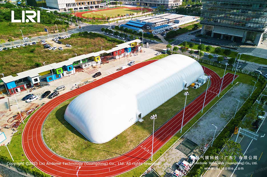 Air dome covering an outdoor synthetic field and running track seen from a higher aerial angle