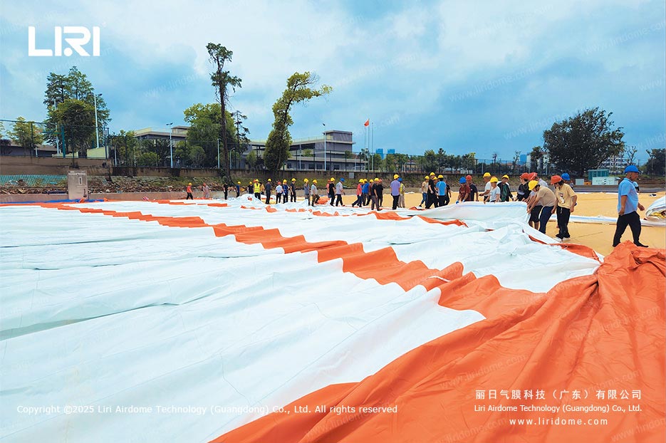 Workers spreading the membrane during on-site air dome gymnasium installation