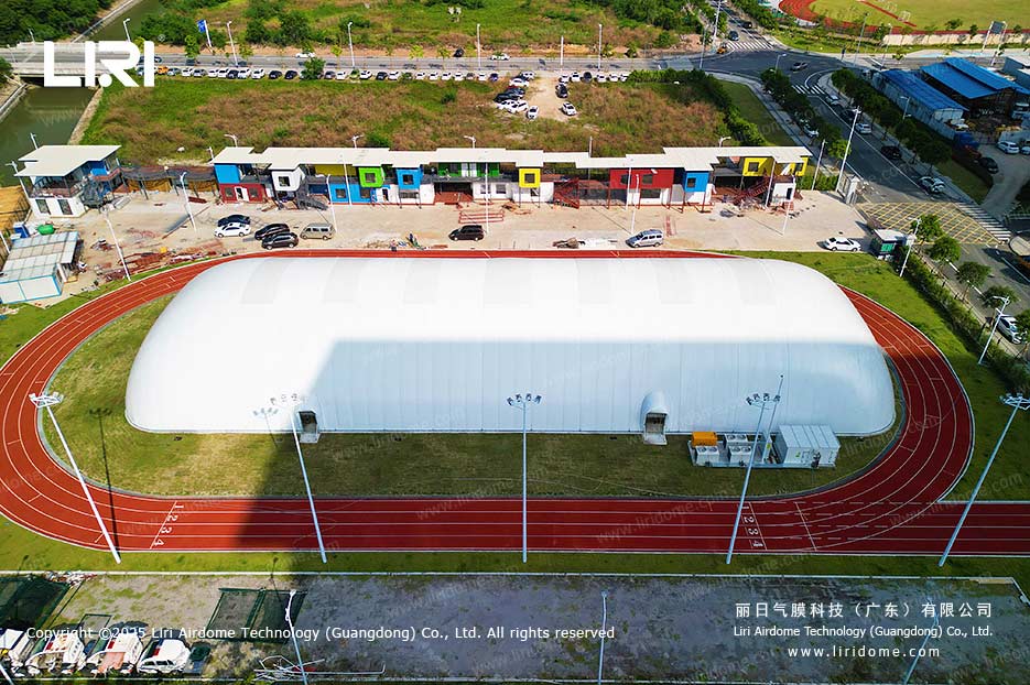 Aerial view of a white air dome built over a synthetic sports field enclosed by a red running track
