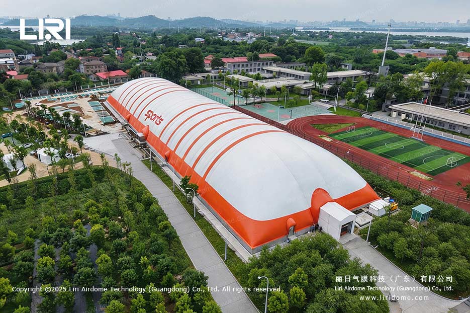 Orange and white air dome sports hall on a lakeside school campus