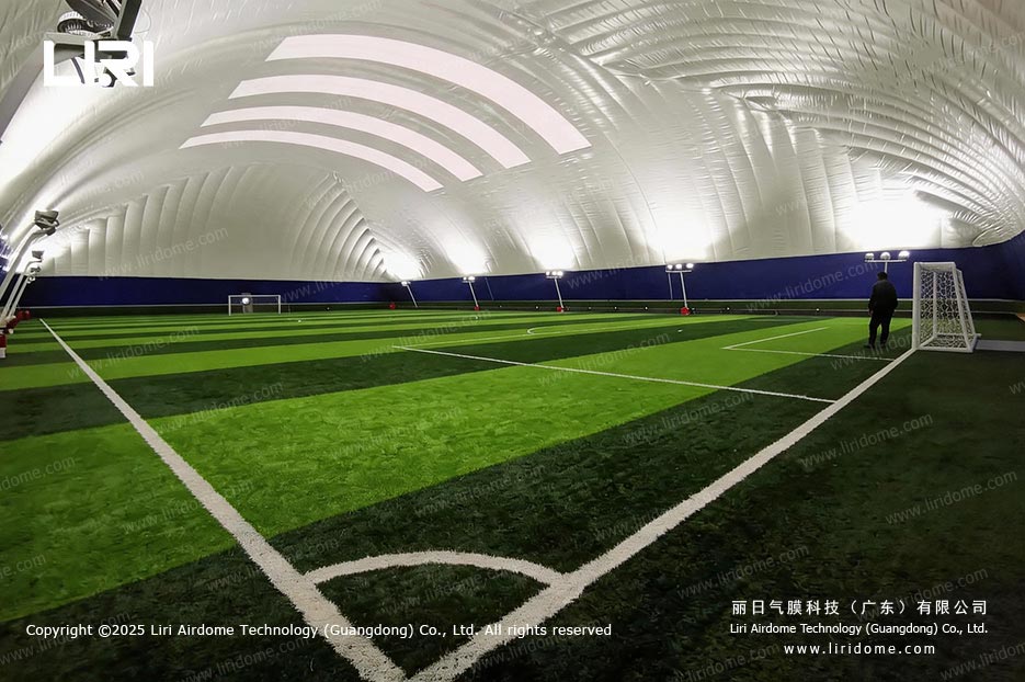 Evening view inside a football air dome with a goal and lit membrane ceiling