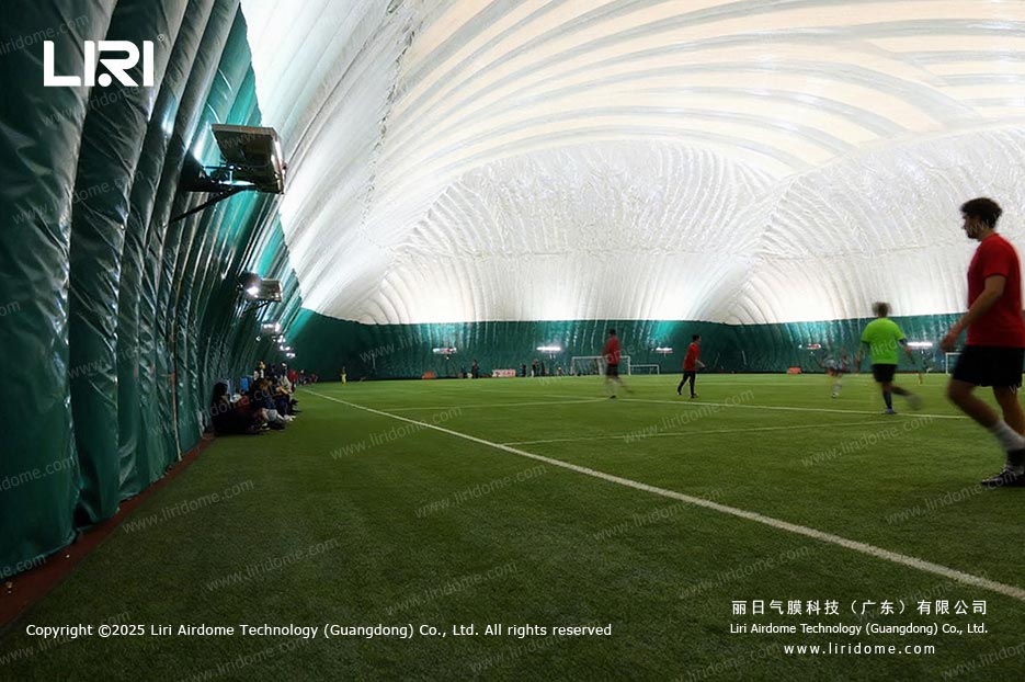 Football players in action inside an air dome with green perimeter walls
