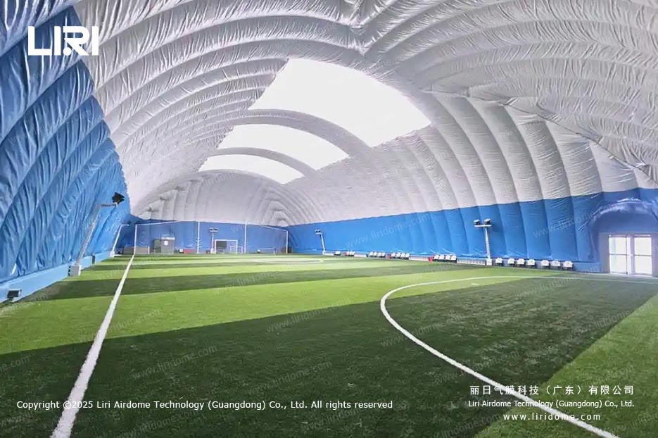 Interior of a football air dome with a green pitch under a bright membrane roof