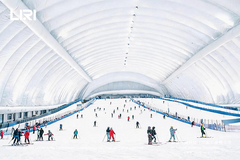 Skiers using a snow slope beneath an insulated air dome roof
