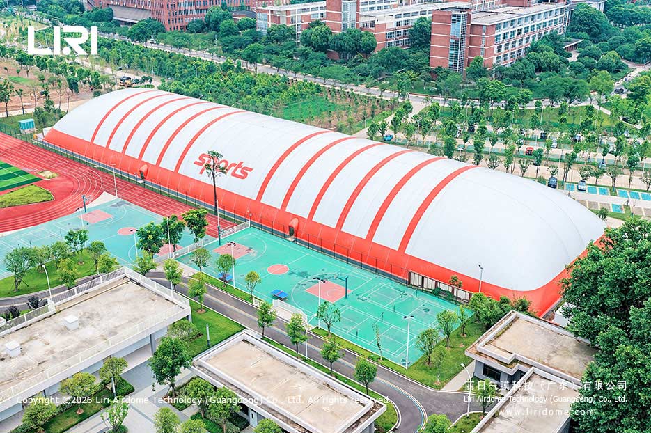 School air dome gymnasium beside outdoor basketball courts and campus buildings