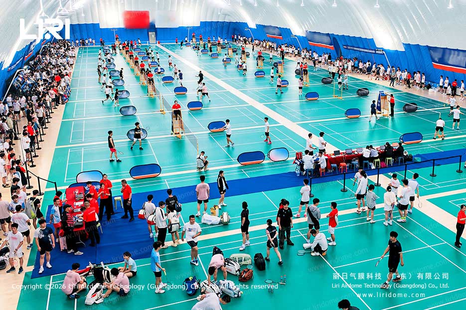 Indoor badminton tournament across multiple courts in a school air dome gymnasium