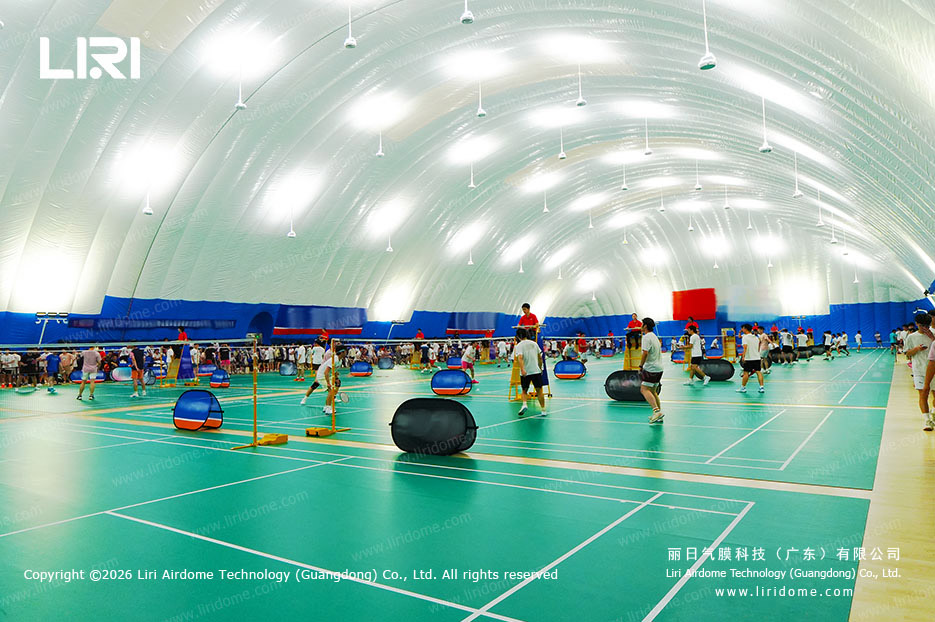 Wide interior view of multiple badminton courts in a school air dome